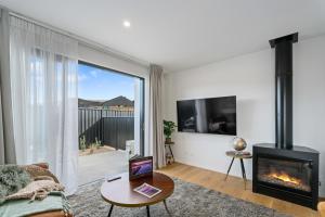 a living room with a fireplace and a tv at Alpine Grandview Luxury Townhouse - Explore Wanaka in Albert Town