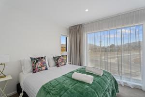 a bedroom with a large bed and a large window at Alpine Grandview Luxury Townhouse - Explore Wanaka in Albert Town