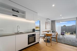a kitchen with white cabinets and a table with a dining room at Alpine Grandview Luxury Townhouse - Explore Wanaka in Albert Town