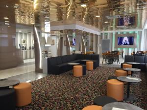 a lobby with couches and tables and a tv at Hôtel Lys de Marie in Lourdes