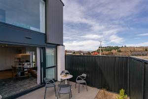 a patio with chairs and a table on a balcony at Alpine Grandview Luxury Townhouse - Explore Wanaka in Albert Town