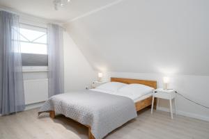 a white bedroom with a bed and a window at Haus Sommerzeit in Fissau