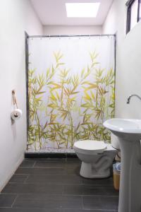 a bathroom with a shower curtain with a toilet and a sink at REEF ON THE WATER in Tamanique