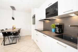 a kitchen with white cabinets and a table with a sink at Haus Titania Wohnung 2 in Grömitz
