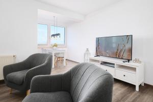a living room with two chairs and a flat screen tv at Promenade 27 Koje 23 in Stakendorfer Strand