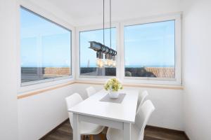 a white dining room with windows and a white table and chairs at Promenade 27 Koje 23 in Stakendorfer Strand