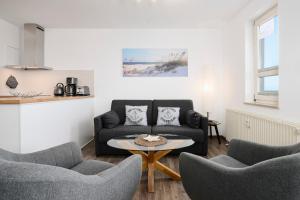 a living room with a couch and chairs and a table at Promenade 27 Koje 23 in Stakendorfer Strand