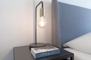 沙博伊茨Haus Meeresstrand BeachBude Scharbeutz的床头的台灯和桌子上的一本书