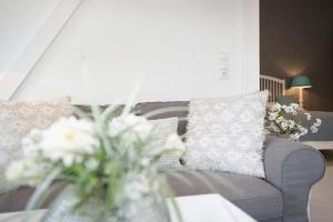 a living room with a gray couch and flowers at Golfplatz Plöner See Großer Plöner See in Bosau +34 photos