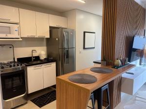 a kitchen with a counter with a refrigerator and a stove at Apartamento mobiliado na Capital do Vinho (Bento) in Bento Gonçalves