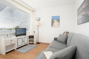 a living room with a couch and a tv at Strandhotel Scharbeutz Kleine Krabbe in Scharbeutz