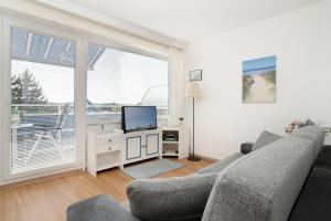 a living room with a couch and a television at Strandhotel Scharbeutz Kleine Krabbe in Scharbeutz