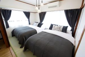 Dos camas en una habitación con ventanas. en 寛永寺坂ハイム 803 東京観光の拠点に最適 鶯谷駅2分, en Tokio