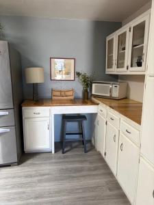 a kitchen with white cabinets and a table with a stool at The Bird House in Sierra Vista