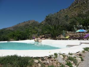 a pool on a beach with a mountain in the background at Villa Paladino Solunto in Santa Flavia