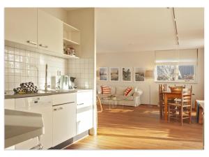 a kitchen with white cabinets and a living room at Holiday Home in Terherne near Scenic Friesland in Terherne