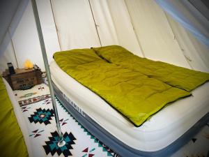ein Bett in einem Zelt mit einer gelben Decke darauf in der Unterkunft ALL SEASON CAMP - Vacation STAY 21071v in Biei