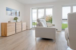 Sala de estar blanca con silla y armario en Haus Seeblick Bosau Abendröte, en Bosau