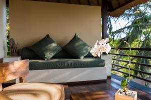 a green couch sitting on a porch with a table at Qunci Villas Resort in Senggigi