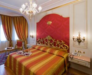 a bedroom with a king sized bed and a chandelier at Hotel Regina Palace in Stresa