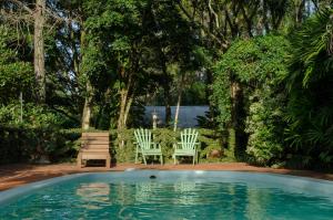 a swimming pool with two chairs and a bench at Canto de Pájaros in Wanda