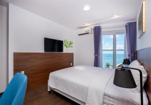 ブンタウにあるCăn hộ Mermaid Seaside Vũng Tàu - THのベッドと大きな窓のある寝室