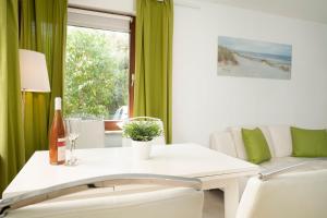 a living room with a white table and green curtains at Zwergi in Grömnitzerhagen