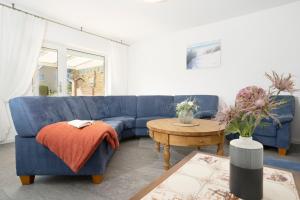 un salon avec un canapé bleu et une table dans l'établissement Ferienhaus Nachtmann, à Kellenhusen