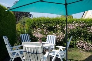 3 chaises et une table avec un parapluie bleu dans l'établissement Ferienhaus Nachtmann, à Kellenhusen