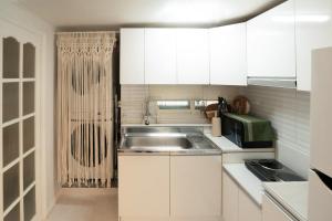 a kitchen with white cabinets and a sink at Ahn-sik, 安息 in Seoul