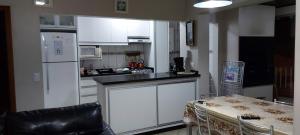 a kitchen with white cabinets and a table and a refrigerator at Ed. Praia de Palmas SC in Governador Celso Ramos