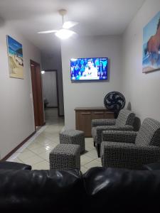 a living room with a couch and chairs and a tv at Ed. Praia de Palmas SC in Governador Celso Ramos