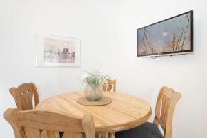 einen Holztisch mit Stühlen und einen TV an der Wand in der Unterkunft Ostseegarten Goldulme in Kellenhusen