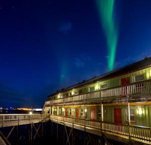 a building with the aurora above it at night at Grønnbuene Rorbu Hotel in Andenes