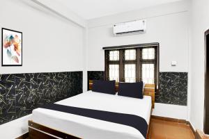 a bedroom with a white bed with blue pillows at Hotel O Azhar lodge in Calicut