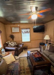 een woonkamer met een plafondventilator en een bank bij Shady Pine Cabin in Benton