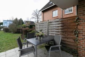 a patio with a table and chairs next to a fence at Seepark Strandglück in Scharbeutz