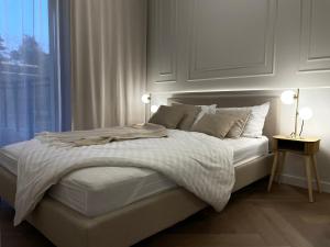 Un dormitorio con una cama blanca con una ventana. en Apartamenty Premium Przy Plaży Morzlive, en Ustronie Morskie