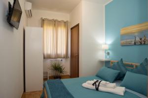 1 dormitorio con 1 cama azul y TV en Bed & breakfast Giulio, en Noto