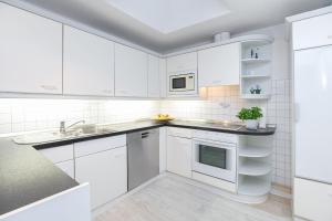 une cuisine blanche avec des armoires blanches et un évier dans l'établissement Haus Seestern Grömitz Strandzauber, à Grömitz
