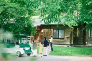 a family standing outside of a house with a golf cart at Karuizawa Prince Hotel West in Karuizawa