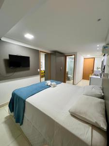 a bedroom with a large white bed with a flat screen tv at GUEST Manaíra Shopping in João Pessoa +23 photos