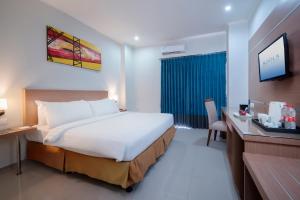 a bedroom with a bed and a desk and a television at Noola Hotel Cilacap in Gumilir