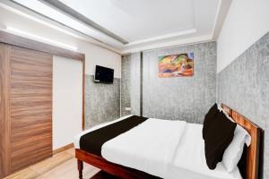 ガーズィヤーバードにあるHotel O Knights Innのベッドと壁掛けテレビのある寝室