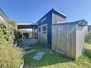 une maison en bois avec une terrasse et une table dans l'établissement Séjour en Tiny House à Jullouville, piscine et parking inclus - FR-1-361A-95, à Jullouville