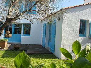 a white house with blue doors and a yard at Maison noirmoutrine confortable pour 7 pers avec jardin et parking - FR-1-823-152 in Noirmoutier-en-l'lle