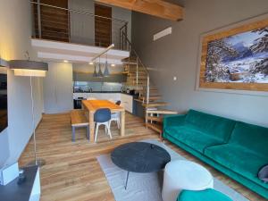 a living room with a green couch and a table at Duplex de luxe 96m² - Terrasse - Ski au pied - 9 Pers. - FR-1-445-221 in Montgenèvre