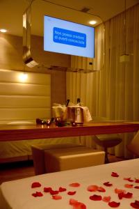 a room with a bed and a television with roses on a table at AmbientHotels Panoramic in Rimini