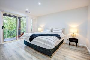a white bedroom with a large bed and a window at Lakeview Family Retreat Canberra Cozy Townhouse in Gungahlin