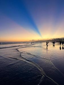 a group of people walking on the beach at sunset at Apartamento completo com 2 suítes in Praia Grande